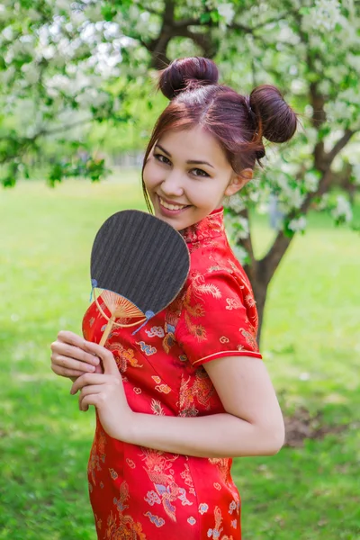 Beautiful asian girl with fan in traditional chinese red dress. — Stock Photo, Image