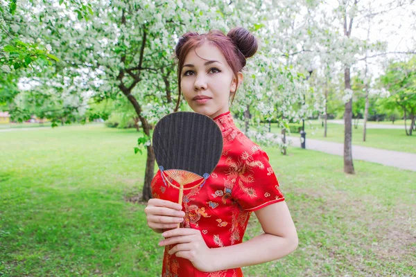 Beautiful asian girl with fan in traditional chinese red dress.