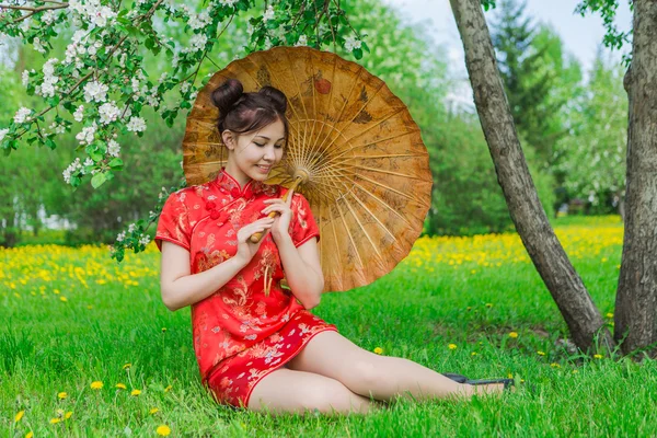 Menina asiática bonita em vestido vermelho chinês tradicional com guarda-chuva de bambu . — Fotografia de Stock