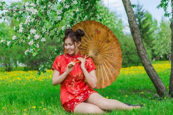 Vackra asiatiska flicka i traditionell kinesiska röda klänning med bambu paraply. — Stockfoto