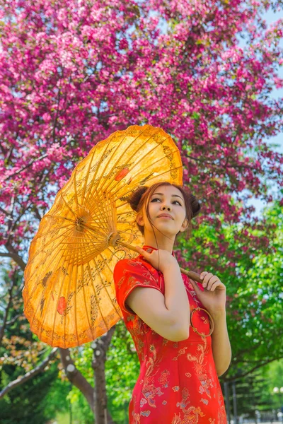 Όμορφο ασιατικό κορίτσι με παραδοσιακή κινεζική κόκκινο φόρεμα με ομπρέλα από μπαμπού. — Φωτογραφία Αρχείου