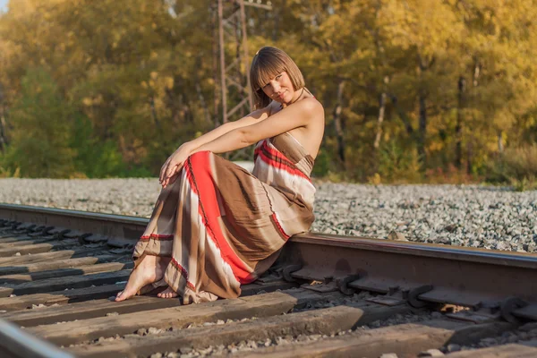 Bella ragazza seduta su binario ferroviario . — Foto Stock