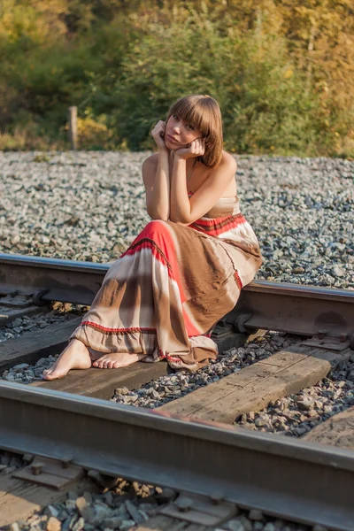 Hermosa chica sentada en la vía férrea . — Foto de Stock