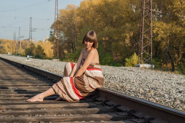 Красива дівчина сидить на залізничній колії . — стокове фото