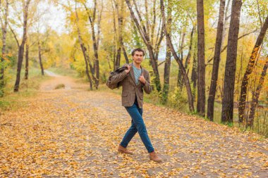 Sonbahar sokağında çantası olan uzun boylu yakışıklı bir adam.