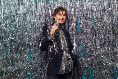 Tatil konsepti. Mutlu, çakırkeyif bir adam. Noel 'de bir bardak şampanyayla ya da parlak bir arka planda yeni yıl partisiyle..