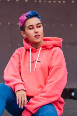 Pembe kapüşonlu kısa saçlı ve burunlu genç kız.