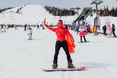 Sheregesh, Kemerovo bölgesi, Rusya - 3 Nisan 2021: Grelka Festivali, karnaval kostümlü kayakçılar ve snowboard sürücüleri için bir spor ve eğlence etkinliğidir. Karnaval kostümlü insanlar kayak ve snowboard yapıyor..