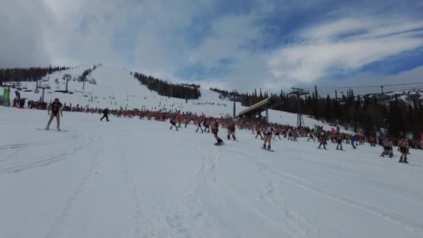 Sheregesh, Kemerovo region, Russia - April 17, 2021: Grelka Fest is a sports and entertainment activity for ski and snowboard riders in bikini. Crowd of people riding snowboard and mountain ski — Stock Video