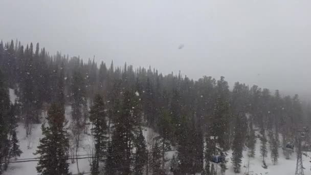 Μετακίνηση ανελκυστήρα σκι κοντά στην πλαγιά του βουνού σε ένα χιονισμένο καιρό — Αρχείο Βίντεο