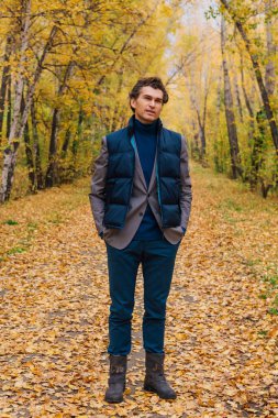 Güz sokağında yürüyen kahverengi ceketli uzun boylu yakışıklı bir adam.