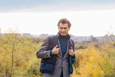 Tepedeki sonbahar ormanında uzun boylu yakışıklı bir adam.