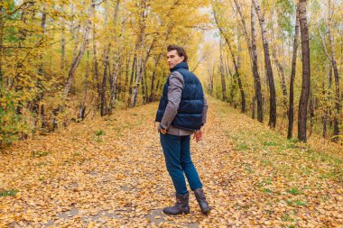 Sonbahar sokağında yürüyen uzun boylu yakışıklı bir adam.