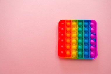 Gökkuşağı duyusal kıpırdaması pembe arka planda izole edilmiş. Yeni moda silikon oyuncak. Patlayan baloncuk silikon oyuncakları.