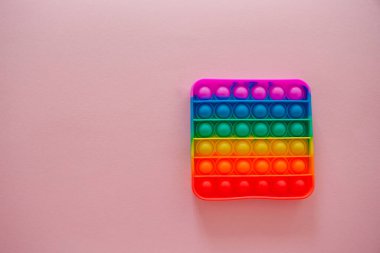 Gökkuşağı duyusal kıpırdaması pembe arka planda izole edilmiş. Yeni moda silikon oyuncak. Patlayan baloncuk silikon oyuncakları.