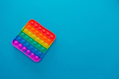 Gökkuşağı duyusal kıpırdaması mavi arka planda izole edilmiş. Yeni moda silikon oyuncak. Patlayan baloncuk silikon oyuncakları.