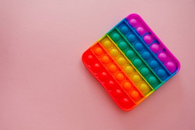 Renkli anti-stres oyuncağını pembe arka plana yerleştir..