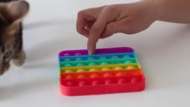 Eller stres önleyici, pop it oyuncağıyla oynar. Gökkuşağı duyusal kıpırdaması beyaz arka planda izole edilmiş. Yeni moda silikon oyuncak. Patlayan baloncuk silikon oyuncakları.