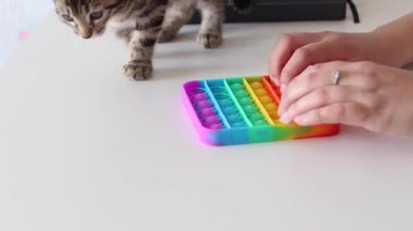 Eller stres önleyici, pop it oyuncağıyla oynar. Gökkuşağı duyusal kıpırdaması beyaz arka planda izole edilmiş. Yeni moda silikon oyuncak. Patlayan baloncuk silikon oyuncakları.