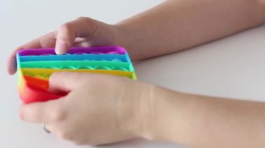 Eller stres önleyici, pop it oyuncağıyla oynar. Gökkuşağı duyusal kıpırdaması beyaz arka planda izole edilmiş. Yeni moda silikon oyuncak. Patlayan baloncuk silikon oyuncakları.
