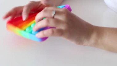 Eller stres önleyici, pop it oyuncağıyla oynar. Gökkuşağı duyusal kıpırdaması beyaz arka planda izole edilmiş. Yeni moda silikon oyuncak. Patlayan baloncuk silikon oyuncakları.