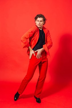 Kırmızı arka planda poz veren uzun boylu, yakışıklı bir adamın portresi..
