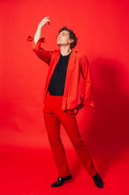 Kırmızı arka planda poz veren uzun boylu, yakışıklı bir adamın portresi..