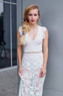 Beyaz gelinlikli güzel sarışın gelin ve açık havada ayna penceresinin yanında duran parlak makyaj..