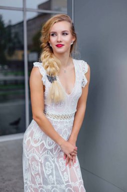 Beyaz gelinlikli güzel sarışın gelin ve açık havada ayna penceresinin yanında duran parlak makyaj..