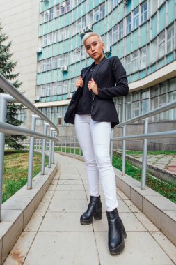 Kısa saçlı ve burnu piercingli şık bir iş kadını. Kendine güvenen kız iş merkezinin yanında duran lezbiyen gibi görünüyor.