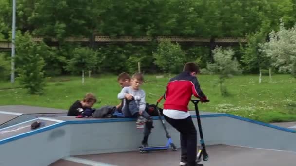 Un grupo de chicos monta un scooter en un parque extremo. Estudio de los deportes extremos al aire libre. — Vídeos de Stock