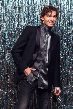 Tatil konsepti. Mutlu, çakırkeyif, şampanyalı ve şarap kadehli adam Noel 'de ya da yeni yıl partisinde parlak bir arka planda..