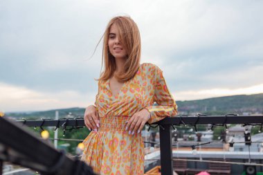 Uzun leopar desenli elbiseli güzel bir kadın bir binanın çatısında merdivenlerde dikiliyor..