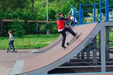 Novokuznetsk, Rusya - 19 Temmuz 2021: Bir grup genç, ekstrem bir parkta scooter kullanıyor. Açık havada ekstrem sporlar eğitimi.