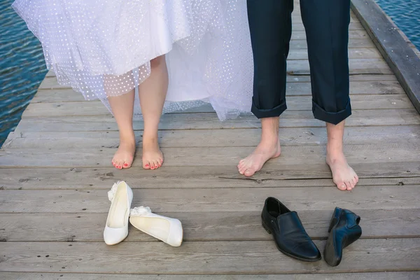 Wedding couple's feet standing on the wooden bridge.