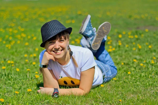 Красива усміхнена молода жінка в капелюсі на траві . — стокове фото