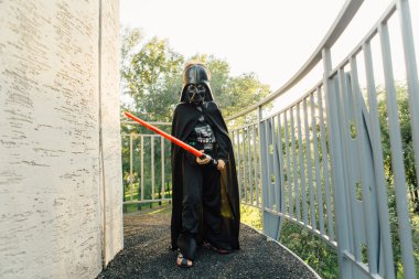 Çocuk bir kostüm Darth Vader kılıç ile.