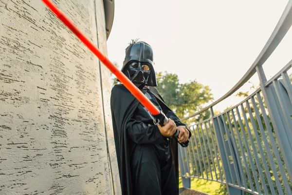 Çocuk bir kostüm Darth Vader kılıç ile.