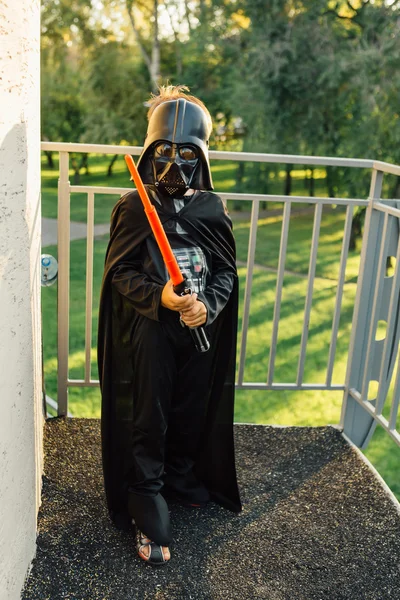 Çocuk bir kostüm Darth Vader kılıç ile.