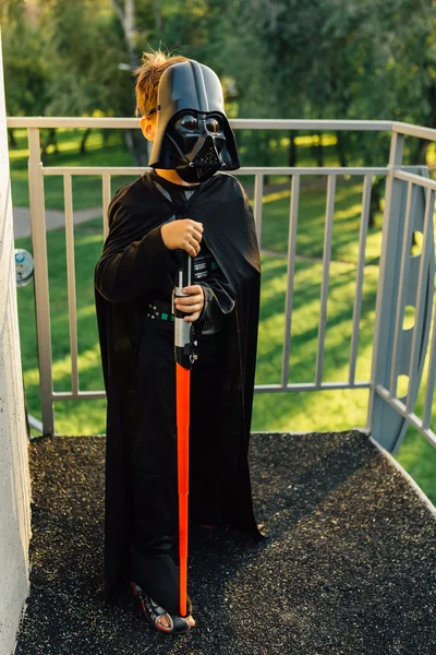 Çocuk bir kostüm Darth Vader kılıç ile.