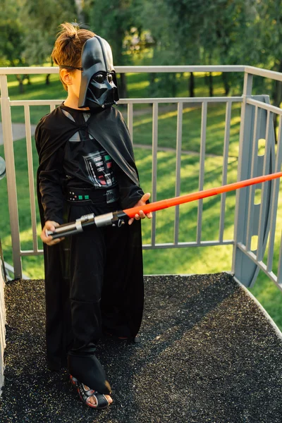 Çocuk bir kostüm Darth Vader kılıç ile.