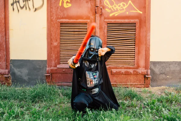 Çocuk bir kostüm Darth Vader kılıç ile.