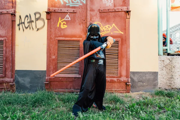 Çocuk bir kostüm Darth Vader kılıç ile.