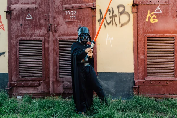 Çocuk bir kostüm Darth Vader kılıç ile.