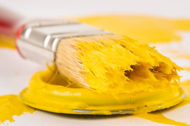 Açık sarı boya kutusunun kapağında kullanılmış boya fırçası var.