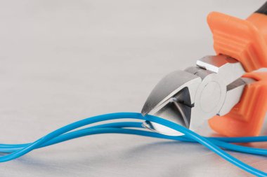 Elektrikli ev kurulumlarında kullanılan metal plaka üzerindeki pense ve kablo.