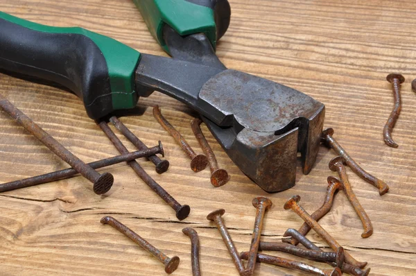 Roestige Tang en nagels op een houten tafel — Stockfoto