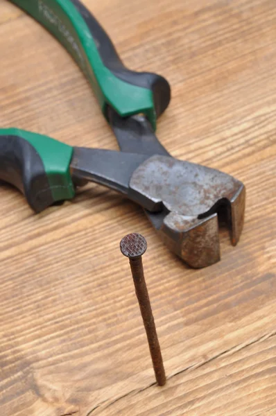 Alicates oxidados y clavos en una mesa de madera — Foto de Stock