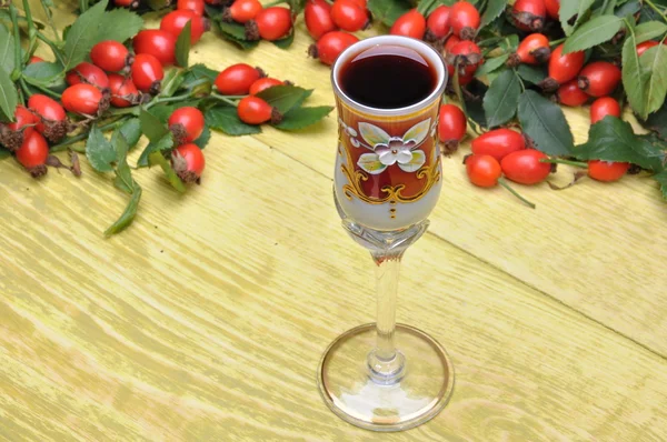 Rosehip fruits et liqueur alcoolisée dans un verre — Photo