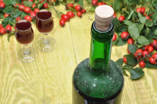 Бутылка ликера, бокалы и фрукты из шиповника — стоковое фото